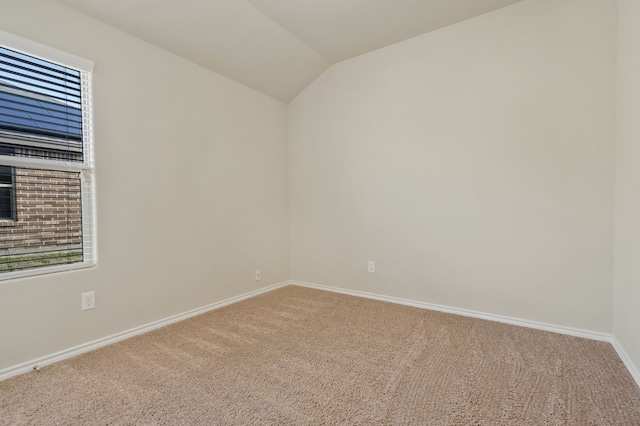 carpeted empty room featuring lofted ceiling