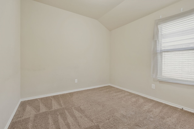 carpeted spare room featuring vaulted ceiling