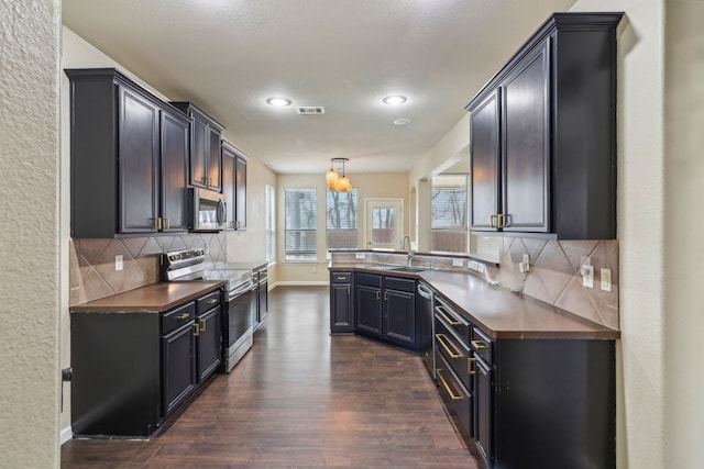 kitchen featuring sink, decorative light fixtures, dark hardwood / wood-style floors, stainless steel appliances, and decorative backsplash