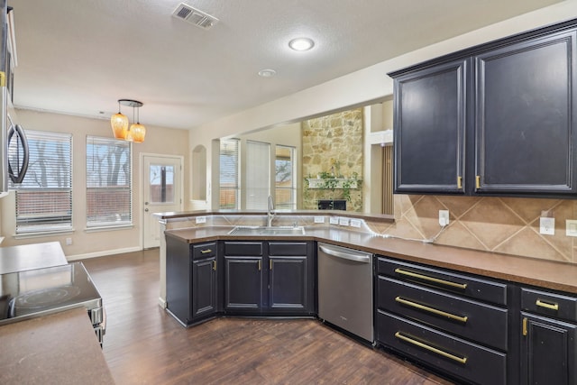 kitchen featuring sink, tasteful backsplash, decorative light fixtures, appliances with stainless steel finishes, and dark hardwood / wood-style floors