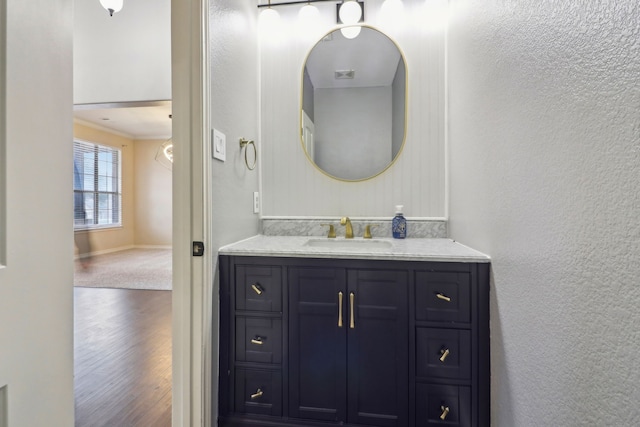 bathroom featuring wood-type flooring, ornamental molding, and vanity