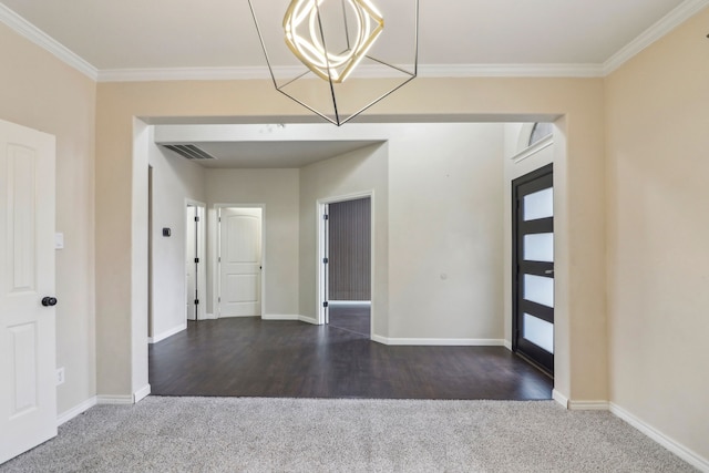 empty room featuring dark wood-type flooring, ornamental molding, and a chandelier