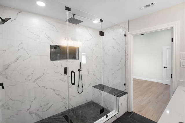 bathroom featuring a shower with shower door and wood-type flooring