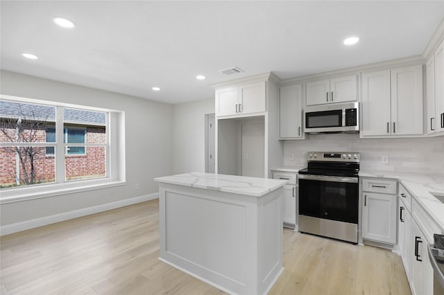 kitchen with appliances with stainless steel finishes, backsplash, light wood-style flooring, and visible vents