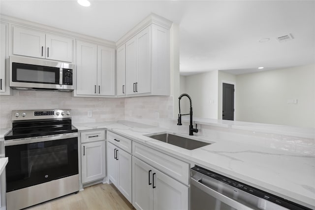 kitchen featuring white cabinetry, sink, light stone countertops, and appliances with stainless steel finishes