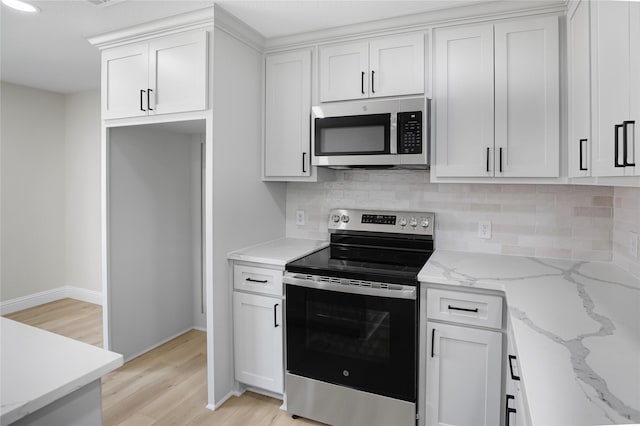 kitchen with white cabinetry, tasteful backsplash, appliances with stainless steel finishes, and light stone counters