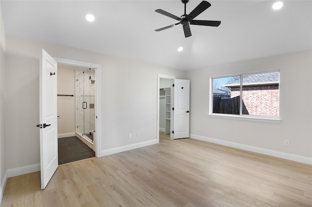 unfurnished bedroom with ensuite bathroom, light hardwood / wood-style floors, a spacious closet, vaulted ceiling, and a closet