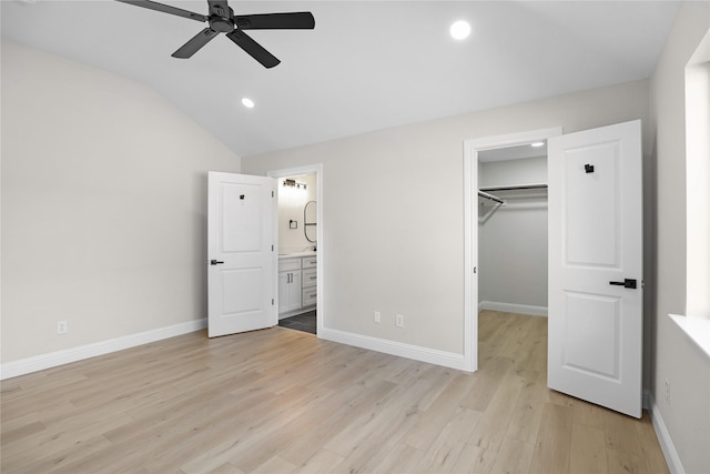 unfurnished bedroom featuring connected bathroom, lofted ceiling, light hardwood / wood-style flooring, a spacious closet, and a closet