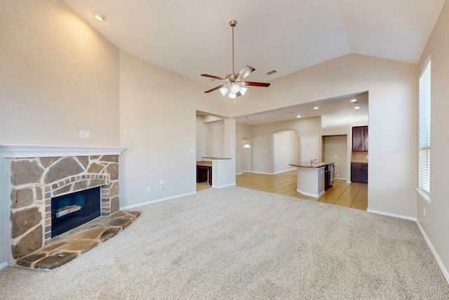 unfurnished living room featuring ceiling fan, light colored carpet, a fireplace, and vaulted ceiling