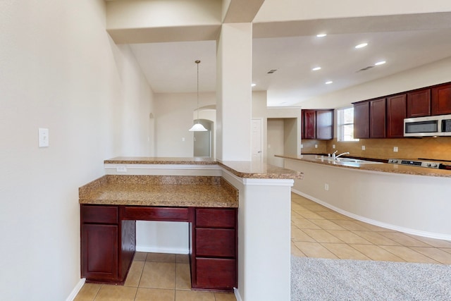 kitchen featuring decorative backsplash, hanging light fixtures, light tile patterned floors, range, and kitchen peninsula