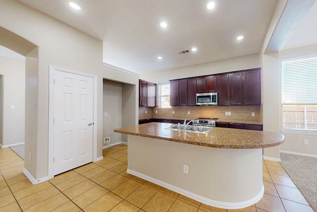 kitchen with tasteful backsplash, sink, an island with sink, and light tile patterned floors