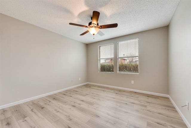 spare room featuring a textured ceiling, light wood-type flooring, a ceiling fan, and baseboards