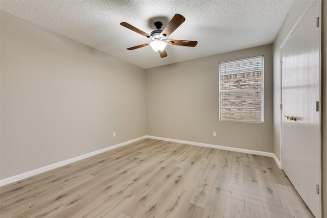 spare room with a ceiling fan, baseboards, light wood-style flooring, and a textured ceiling