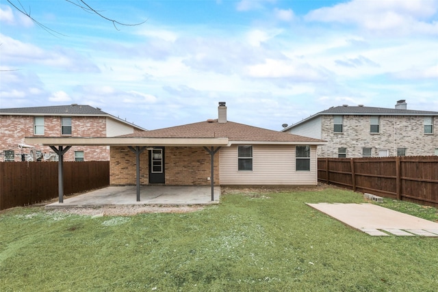 back of property featuring a yard, a fenced backyard, a chimney, and a patio