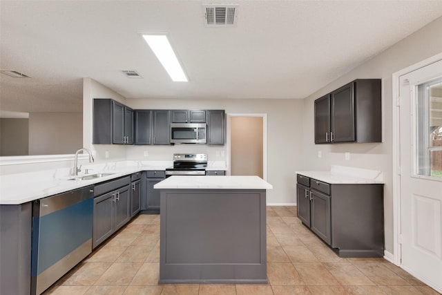 kitchen featuring light tile patterned flooring, sink, gray cabinetry, appliances with stainless steel finishes, and a kitchen island