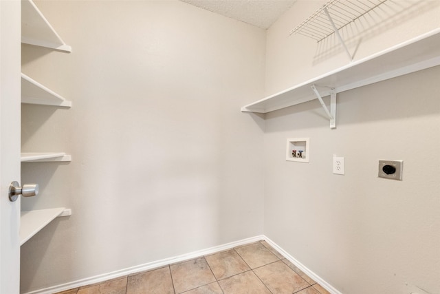 clothes washing area featuring light tile patterned flooring, washer hookup, hookup for an electric dryer, and a textured ceiling