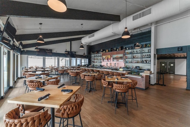 dining area with wood-type flooring, high vaulted ceiling, bar, and beam ceiling