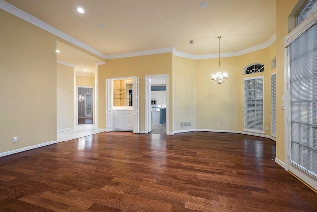 unfurnished room featuring dark hardwood / wood-style flooring, ornamental molding, and a chandelier