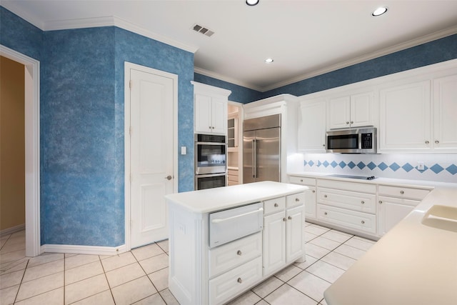 kitchen with stainless steel appliances, ornamental molding, a kitchen island, and white cabinets