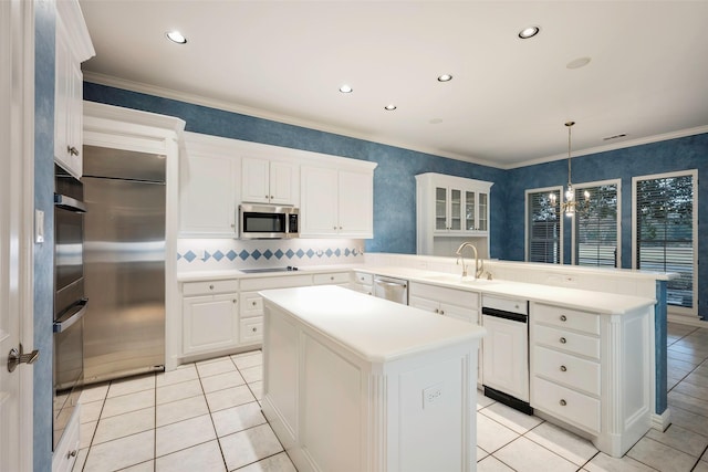 kitchen featuring stainless steel appliances, sink, hanging light fixtures, and a kitchen island