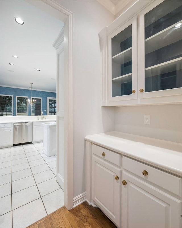 bar featuring decorative light fixtures, sink, white cabinets, stainless steel dishwasher, and light tile patterned floors