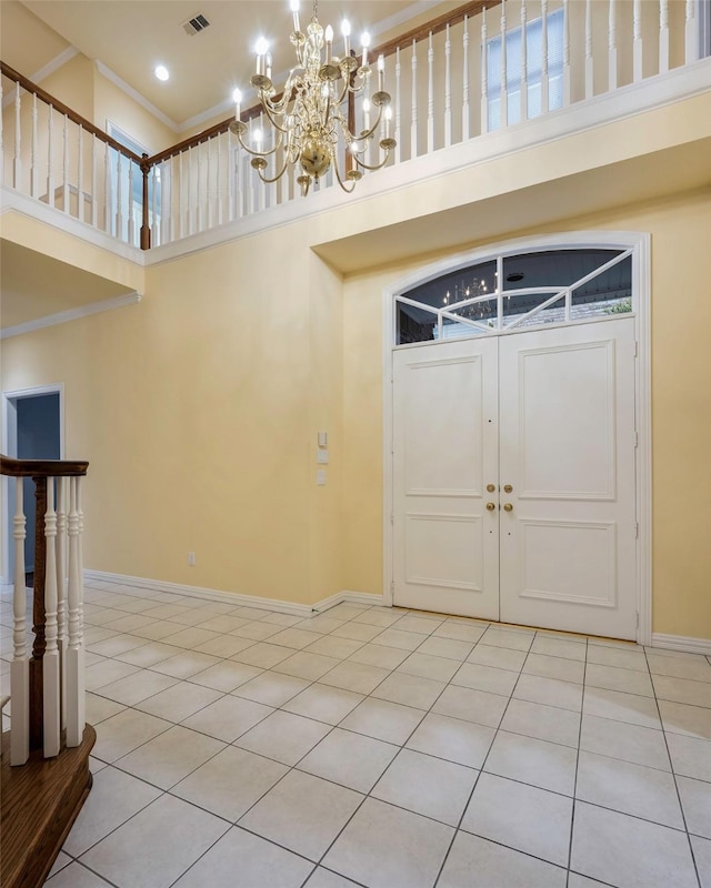 tiled foyer with a notable chandelier, ornamental molding, and a high ceiling