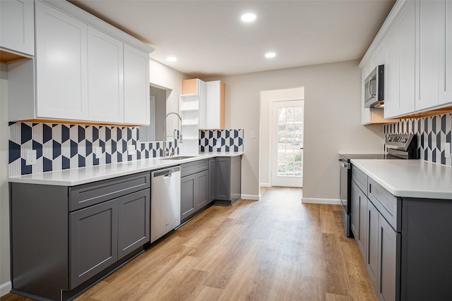 kitchen with sink, gray cabinets, appliances with stainless steel finishes, light hardwood / wood-style floors, and white cabinets