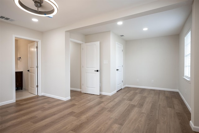 unfurnished bedroom with hardwood / wood-style floors and ensuite bathroom