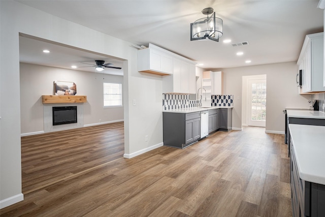 kitchen with gray cabinets, tasteful backsplash, white cabinets, and light wood-type flooring