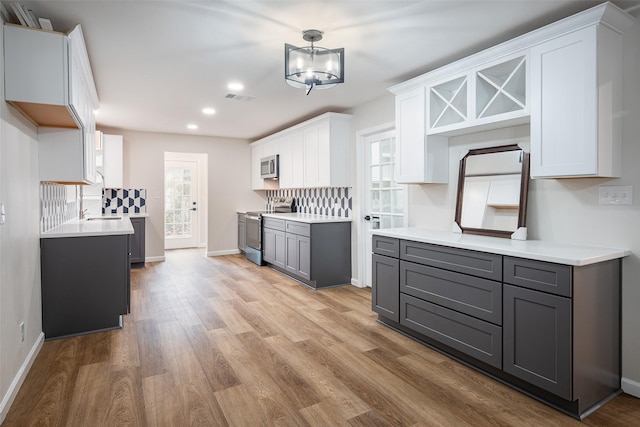 kitchen with white cabinetry, hanging light fixtures, gray cabinets, and appliances with stainless steel finishes