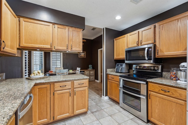 kitchen with crown molding, a textured ceiling, light tile patterned floors, stainless steel appliances, and light stone countertops