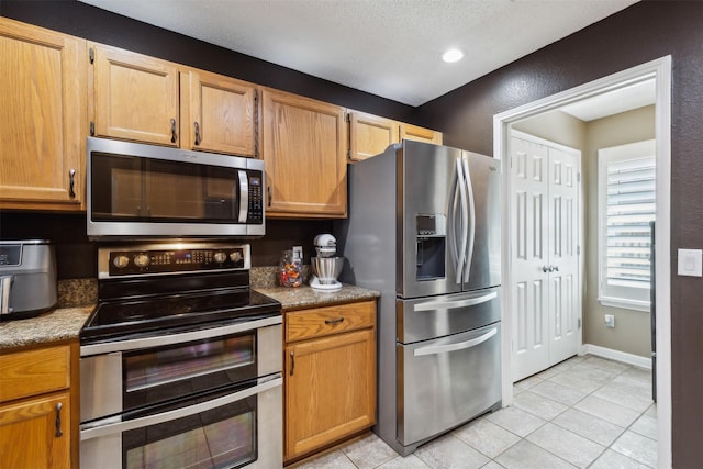 kitchen featuring light tile patterned floors, stainless steel appliances, and a textured ceiling