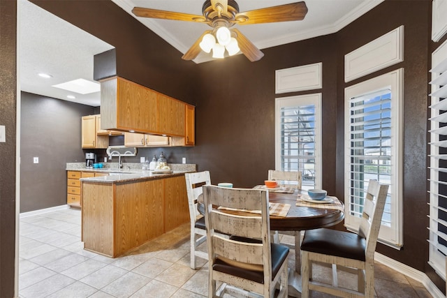 kitchen with sink, light tile patterned floors, ceiling fan, kitchen peninsula, and crown molding