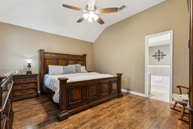 bedroom with vaulted ceiling, dark wood-type flooring, ceiling fan, and ensuite bath