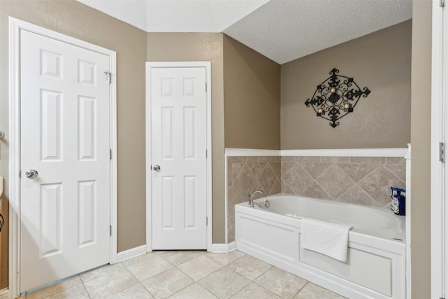 bathroom with tile patterned flooring, a bath, and a textured ceiling