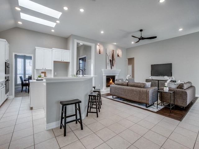 kitchen featuring a warm lit fireplace, light tile patterned flooring, white cabinets, open floor plan, and light countertops