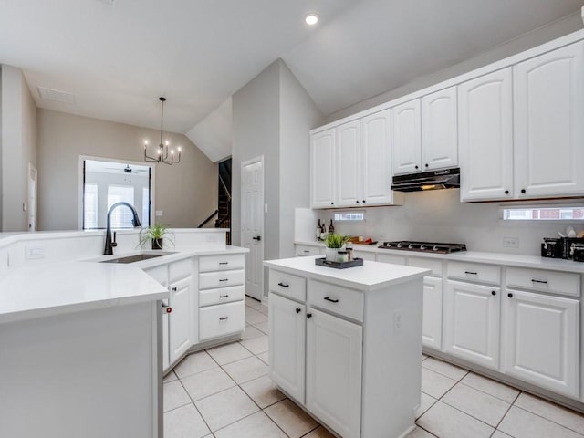 kitchen featuring a center island, gas stovetop, light tile patterned floors, a sink, and under cabinet range hood