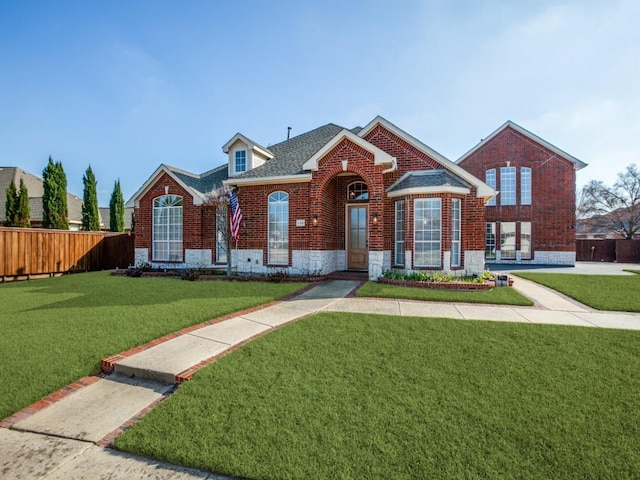 view of front of property featuring a shingled roof, fence, a front lawn, and brick siding