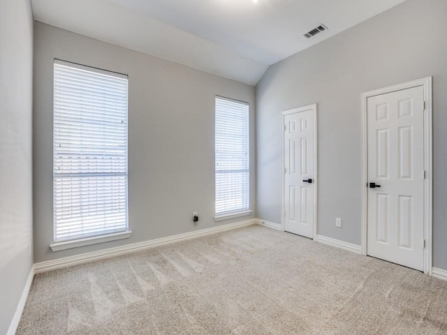 interior space featuring carpet floors, baseboards, visible vents, and lofted ceiling