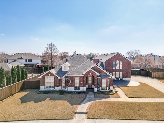 view of front facade featuring brick siding, a front lawn, and fence private yard