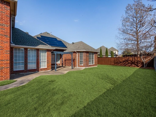 back of house featuring a patio, brick siding, roof with shingles, and a fenced backyard