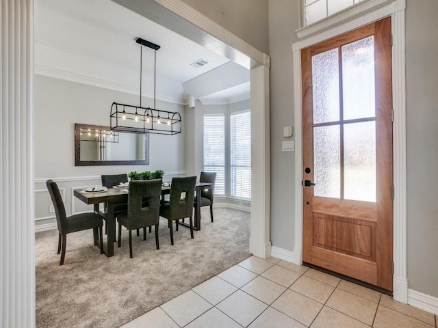 entrance foyer featuring crown molding, a notable chandelier, light tile patterned floors, light colored carpet, and visible vents