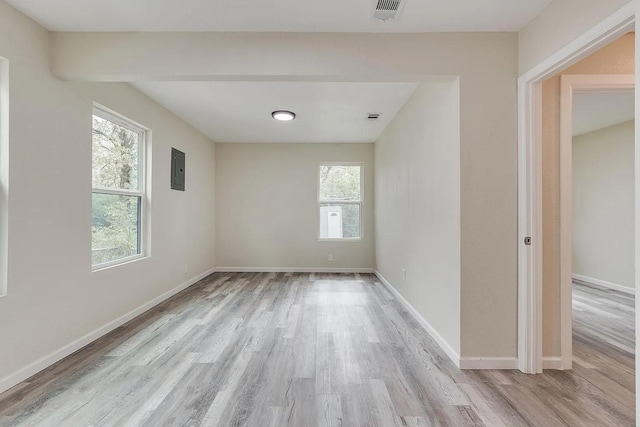 empty room with electric panel and light wood-type flooring