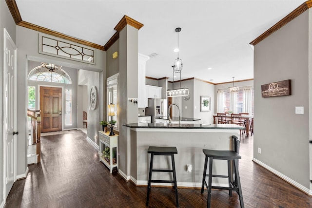 kitchen with pendant lighting, kitchen peninsula, white cabinetry, dark hardwood / wood-style flooring, and stainless steel fridge with ice dispenser