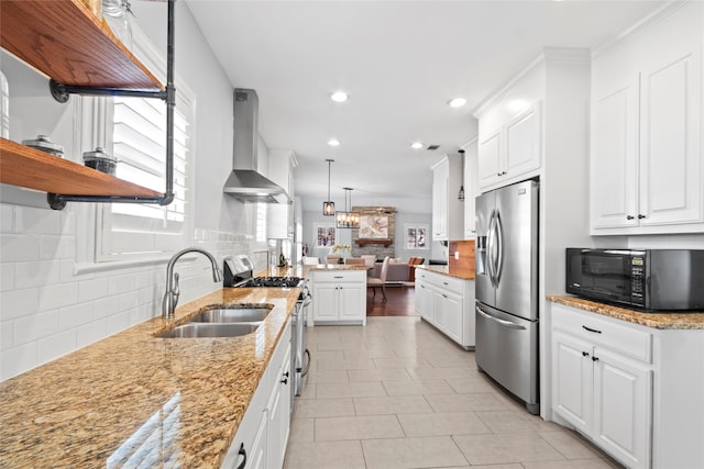 kitchen featuring wall chimney exhaust hood, sink, stainless steel appliances, light stone countertops, and white cabinets