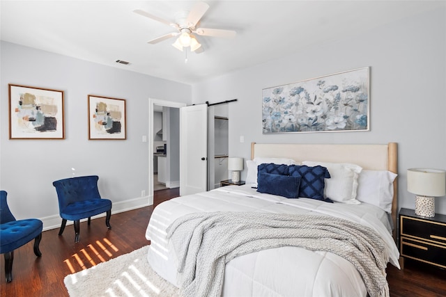 bedroom featuring dark wood-type flooring, ceiling fan, and a barn door