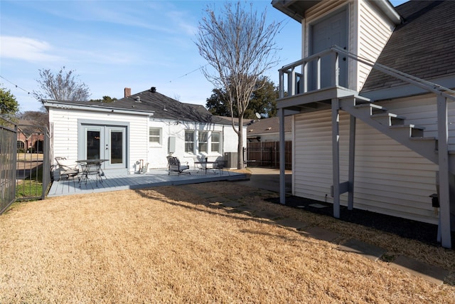 back of property featuring a wooden deck, a lawn, and french doors