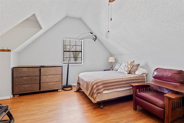 bedroom with ceiling fan, vaulted ceiling, light hardwood / wood-style floors, and a textured ceiling