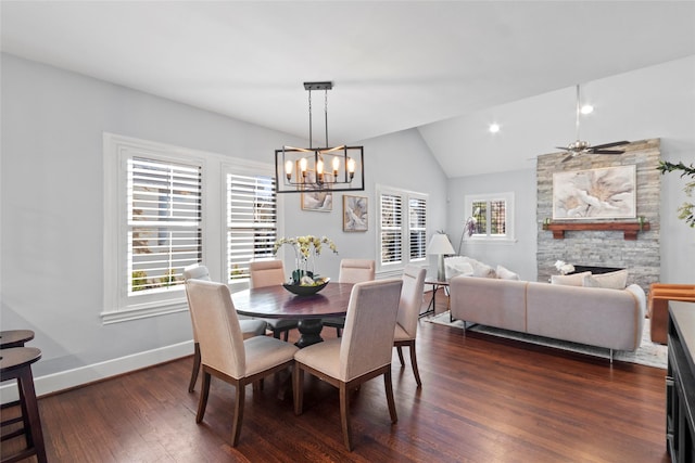 dining area featuring lofted ceiling, dark wood-type flooring, plenty of natural light, and a stone fireplace