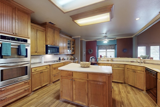 kitchen featuring a wealth of natural light, light hardwood / wood-style flooring, a center island with sink, and black appliances